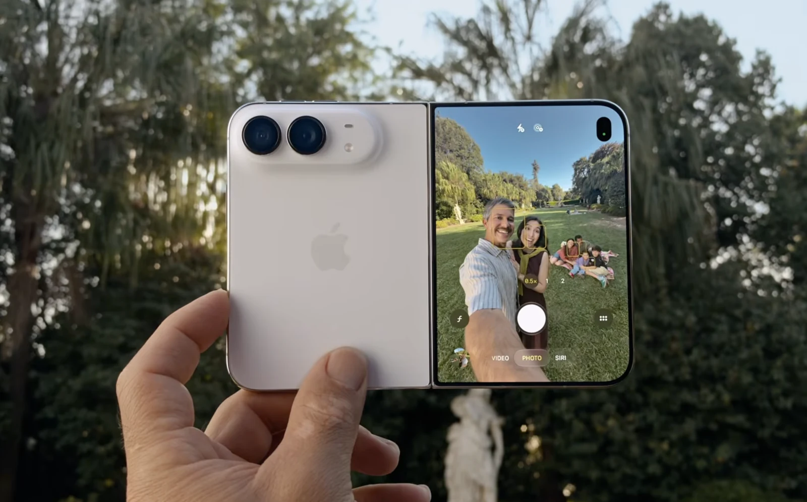 접은 iPhone Duo 를 한 손으로 들고 있는 발표 사진. 뒷면 카메라가 앞을 향하고 바깥 화면에는 촬영되는 사람들의 모습이 미리 보인다