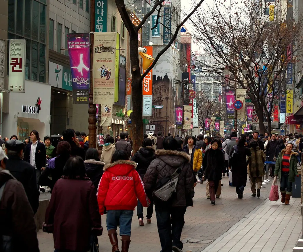 상점과 간판이 늘어선 서울 명동 쇼핑 거리를 걷는 사람들